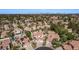 Aerial view highlighting a residential community with terracotta roofs, mature trees, and private pools amidst a city backdrop at 227 Drysdale Cir, Henderson, NV 89074