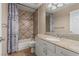 Tiled bathroom featuring a shower-tub combination, decorative tiles, and a granite-topped vanity with modern fixtures at 227 Drysdale Cir, Henderson, NV 89074
