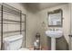 Simple bathroom features a pedestal sink, toilet, tiled floors, and shelving unit for toiletries at 227 Drysdale Cir, Henderson, NV 89074
