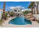 Backyard featuring a pool, rock waterfall and spa, palm trees, and covered outdoor living space at 227 Drysdale Cir, Henderson, NV 89074