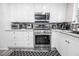 Close-up of a sleek kitchen boasting stainless steel appliances, white cabinetry, and stylish backsplash at 3018 Sunrise Bay Ave, North Las Vegas, NV 89031