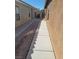 Narrow side yard of a single story house, with gravel and a cemented path at 3425 Palatine Hills Ave, North Las Vegas, NV 89081