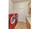 Laundry room features modern red washer and dryer set, tile flooring, and white cabinets at 3540 Wisdom Ct, Las Vegas, NV 89120