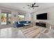 Bright living room with neutral walls, tile floors, ceiling fan, large windows and a blue sofa at 4531 S Bay Tree Ct, Pahrump, NV 89061