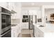 Modern, white kitchen with stainless steel appliances, large island, and tile backsplash at 59 Reflection Bay Dr, Henderson, NV 89011