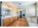 En-suite bathroom with dual vanities, soaking tub, and wood-look flooring at 6141 Babson Ave, Las Vegas, NV 89110