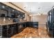 The kitchen has black cabinetry, stainless appliances, granite countertops, and eye-catching flooring at 6141 Babson Ave, Las Vegas, NV 89110