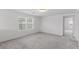 Neutral-colored, carpeted bedroom with two windows and entrance to another room at 6955 Elysian Valley Ave, Las Vegas, NV 89113