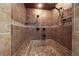 Step-in shower featuring custom tile work, multiple shower heads, and a built-in bench for added comfort at 728 N Kiel St, Henderson, NV 89015