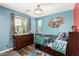 Cozy bedroom with blue walls, wood floors, and a large window offering natural light at 731 Glowing Horizon St, Henderson, NV 89052