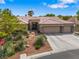 Tan home with a tile roof, three-car garage, and desert landscaping at 7401 Bridlehorne Ave, Las Vegas, NV 89131