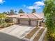 Exterior of a tan home featuring a tile roof, three-car garage, and desert landscaping at 7401 Bridlehorne Ave, Las Vegas, NV 89131
