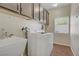 Convenient laundry room featuring front loading washer and dryer, utility sink, and storage at 776 Flowing Meadow Dr, Henderson, NV 89014