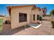 View of backyard with desert landscaping, stucco walls, patio, and small security door at 8028 Hurricane Cove Ct, Las Vegas, NV 89129