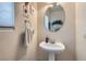 Cozy bathroom with pedestal sink, round mirror, and decorative wall art at 890 Socorro Song Ln, Henderson, NV 89052