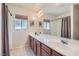 Bright bathroom with double sinks, wood cabinets, a large mirror, and natural light at 890 Socorro Song Ln, Henderson, NV 89052