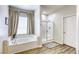 Bright bathroom featuring a soaking tub, glass enclosed shower, and wood-look flooring at 9535 Vega Carpio Ave, Las Vegas, NV 89178