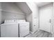 The laundry room with modern washer, dryer, overhead shelf, and stylish gray plank flooring for easy maintenance at 9750 Maple Sugar Leaf Pl, Las Vegas, NV 89148