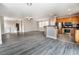 Open-concept living area featuring gray wood-look floors, a ceiling fan, and a view of the kitchen at 9750 Maple Sugar Leaf Pl, Las Vegas, NV 89148