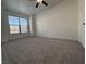 This large bedroom has neutral carpet, a ceiling fan, and a bright window overlooking the neighborhood at 9975 Peace Way # 1140, Las Vegas, NV 89147