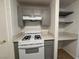 Close-up view of kitchen features gray cabinets, white oven range, quartz countertops, and desk area at 9975 Peace Way # 1140, Las Vegas, NV 89147