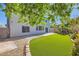 A view of the spacious yard features lush lawn, mature trees, patio, and a block wall at 10654 Robin Hill Ave, Las Vegas, NV 89129