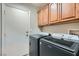 Functional laundry area features wood cabinets and modern, dark front-load washer and dryer set at 10654 Robin Hill Ave, Las Vegas, NV 89129