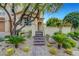 Lush landscaping with desert plants and trees leads to the home's gated entrance at 12122 High Country Ln, Las Vegas, NV 89138