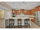 Gourmet kitchen showcasing wooden cabinetry, stainless steel appliances, and a waterfall island with bar seating at 12122 High Country Ln, Las Vegas, NV 89138
