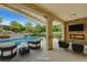 Inviting covered patio with a pool view, stone fireplace, and comfortable seating at 12122 High Country Ln, Las Vegas, NV 89138