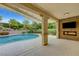 Inviting pool area with an outdoor fireplace, TV, covered patio, and landscaping at 12122 High Country Ln, Las Vegas, NV 89138