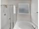 Bright bathroom with a tub-shower combo, glass door, and a window, offering a serene retreat at 138 Scarlett View Ave, North Las Vegas, NV 89031
