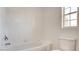 This bathroom showcases white tiled walls and a window, along with a bathtub and toilet at 1890 Bova Matrina Ct, Las Vegas, NV 89123