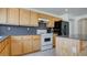 Functional kitchen featuring wood cabinets, modern appliances, and a cozy breakfast bar at 1890 Bova Matrina Ct, Las Vegas, NV 89123