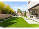 Manicured backyard with seating area, kitchen, and lush artificial grass for low-maintenance enjoyment at 2407 Ridgeline Wash St, Las Vegas, NV 89138