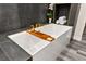 Close-up on a modern, white bathtub with gold fixtures and a wooden bath caddy at 2407 Ridgeline Wash St, Las Vegas, NV 89138