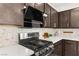Close-up of the modern kitchen featuring stainless steel gas range, a sleek black hood, and granite countertops at 2407 Ridgeline Wash St, Las Vegas, NV 89138