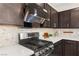 Modern kitchen featuring stainless steel gas range and sleek black hood, with granite countertops and ample space at 2407 Ridgeline Wash St, Las Vegas, NV 89138