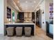 Sleek modern kitchen boasts dark cabinetry, stone countertops, and an island with seating at 28 Painted Feather Way, Las Vegas, NV 89135