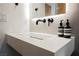 Close-up of floating bathroom sink featuring modern faucet and soap bottles against a textured wall and lit mirror at 5077 Thunder River Cir, Las Vegas, NV 89148