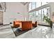 Bright living room features a soaring ceiling, large windows and comfortable orange curved couches and a patterned rug at 5077 Thunder River Cir, Las Vegas, NV 89148