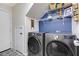 A laundry room featuring a gray front-load washer and dryer, storage shelves and unique patterned tile flooring at 5213 Welch Valley Ave, Las Vegas, NV 89131