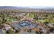 An aerial view showcases a community with tennis courts, a pond, golf course, and surrounding homes at 5240 Las Cruces Dr, Las Vegas, NV 89130