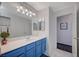 Bright bathroom with a blue vanity, white countertop, large mirror, and marble floors at 5508 Lochmor Ave, Las Vegas, NV 89130