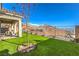 Spacious backyard featuring a patio, lush green turf, desert landscaping, and mountain views at 56 Tatahatso Point St, Henderson, NV 89011