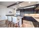 Stylish kitchen with dark cabinetry, stainless steel appliances, a marble countertop island and wood-look tile flooring at 56 Tatahatso Point St, Henderson, NV 89011