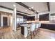 Modern kitchen featuring dark cabinets, stainless steel appliances, a marble island, and wood-look tile flooring at 56 Tatahatso Point St, Henderson, NV 89011