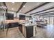 Spacious kitchen with marble island, stainless steel appliances, and black cabinets connected to the living and dining area at 56 Tatahatso Point St, Henderson, NV 89011
