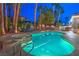 Beautiful in-ground pool with an attached hot tub and lounge chairs surrounded by palm trees at 8808 Rozetta Ct, Las Vegas, NV 89134