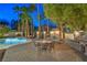Outdoor patio featuring a stone fireplace, outdoor kitchen, and a beautiful in-ground pool with mature landscaping at 8808 Rozetta Ct, Las Vegas, NV 89134